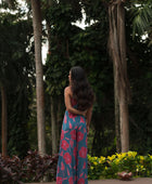 Woman wearing long blue sleeveless jumpsuit with large pink and red floral print.