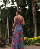 Woman wearing long blue sleeveless jumpsuit with large pink and red floral print.