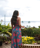 Woman wearing long blue sleeveless jumpsuit with large pink and red floral print.