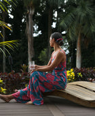 Woman wearing long blue sleeveless jumpsuit with large pink and red floral print.