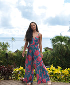 Woman wearing long blue sleeveless jumpsuit with large pink and red floral print.