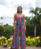 Woman wearing long blue sleeveless jumpsuit with large pink and red floral print.