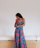 Woman wearing long blue sleeveless jumpsuit with large pink and red floral print.