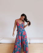 Woman wearing long blue sleeveless jumpsuit with large pink and red floral print.