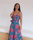 Woman wearing long blue sleeveless jumpsuit with large pink and red floral print.