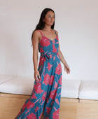 Woman wearing long blue sleeveless jumpsuit with large pink and red floral print.