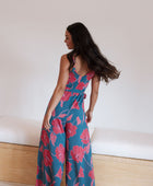 Woman wearing long blue sleeveless jumpsuit with large pink and red floral print.