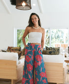 Woman wearing loose blue pants with large pink floral print.