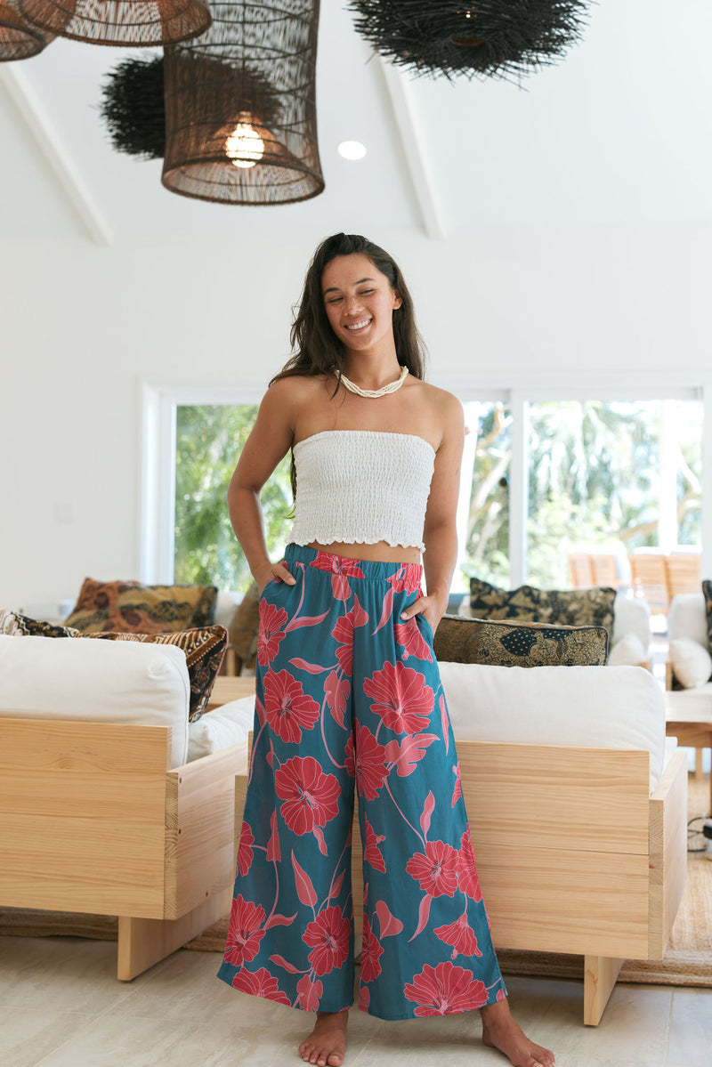 Woman wearing loose blue pants with large pink floral print.