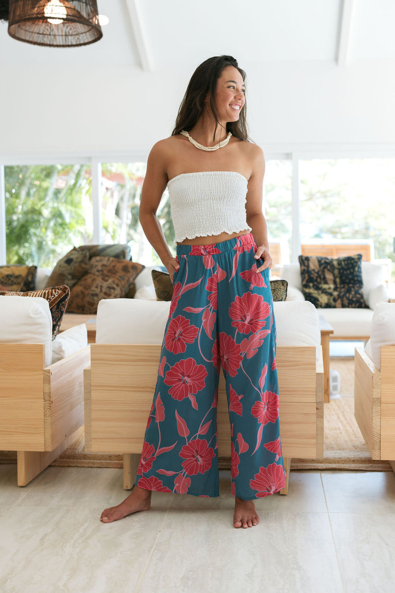 Woman wearing loose blue pants with large pink floral print.