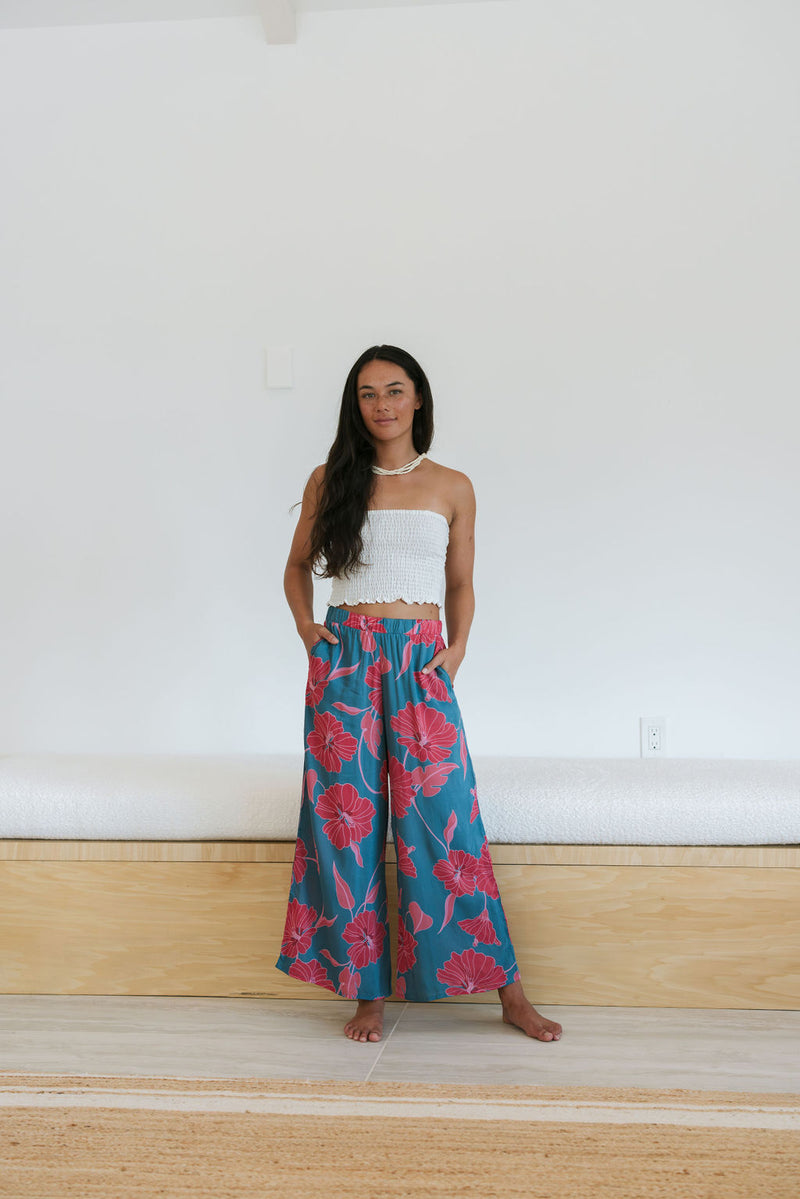 Woman wearing loose blue pants with large pink floral print.