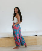 Woman wearing loose blue pants with large pink floral print.