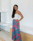 Woman wearing loose blue pants with large pink floral print.