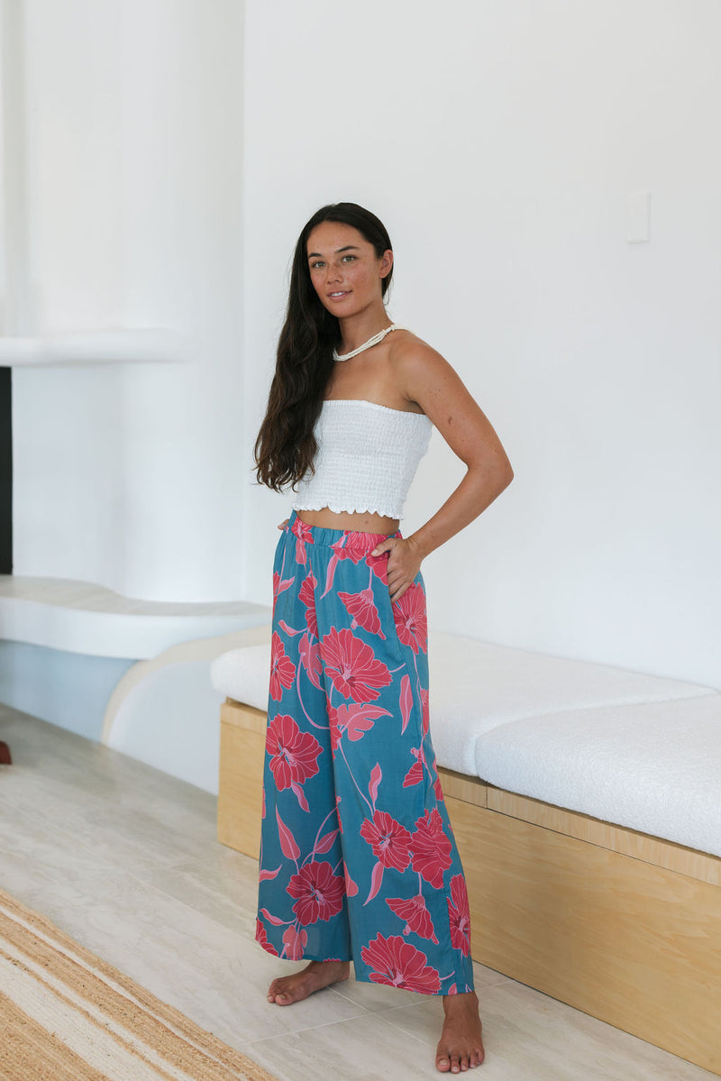 Woman wearing loose blue pants with large pink floral print.