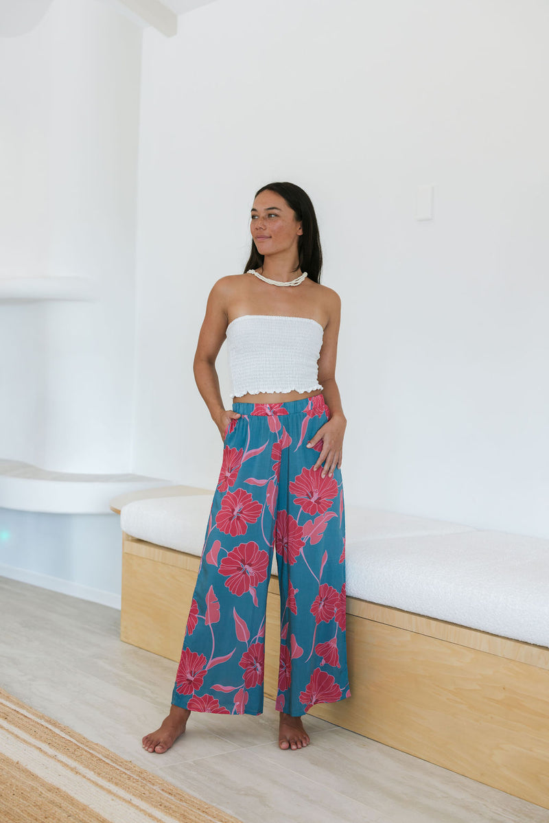 Woman wearing loose blue pants with large pink floral print.