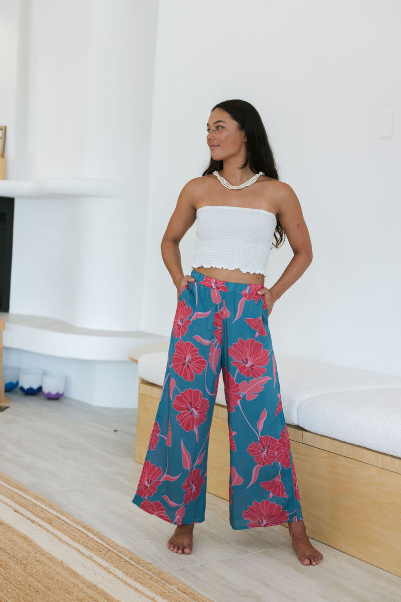 Woman wearing loose blue pants with large pink floral print.