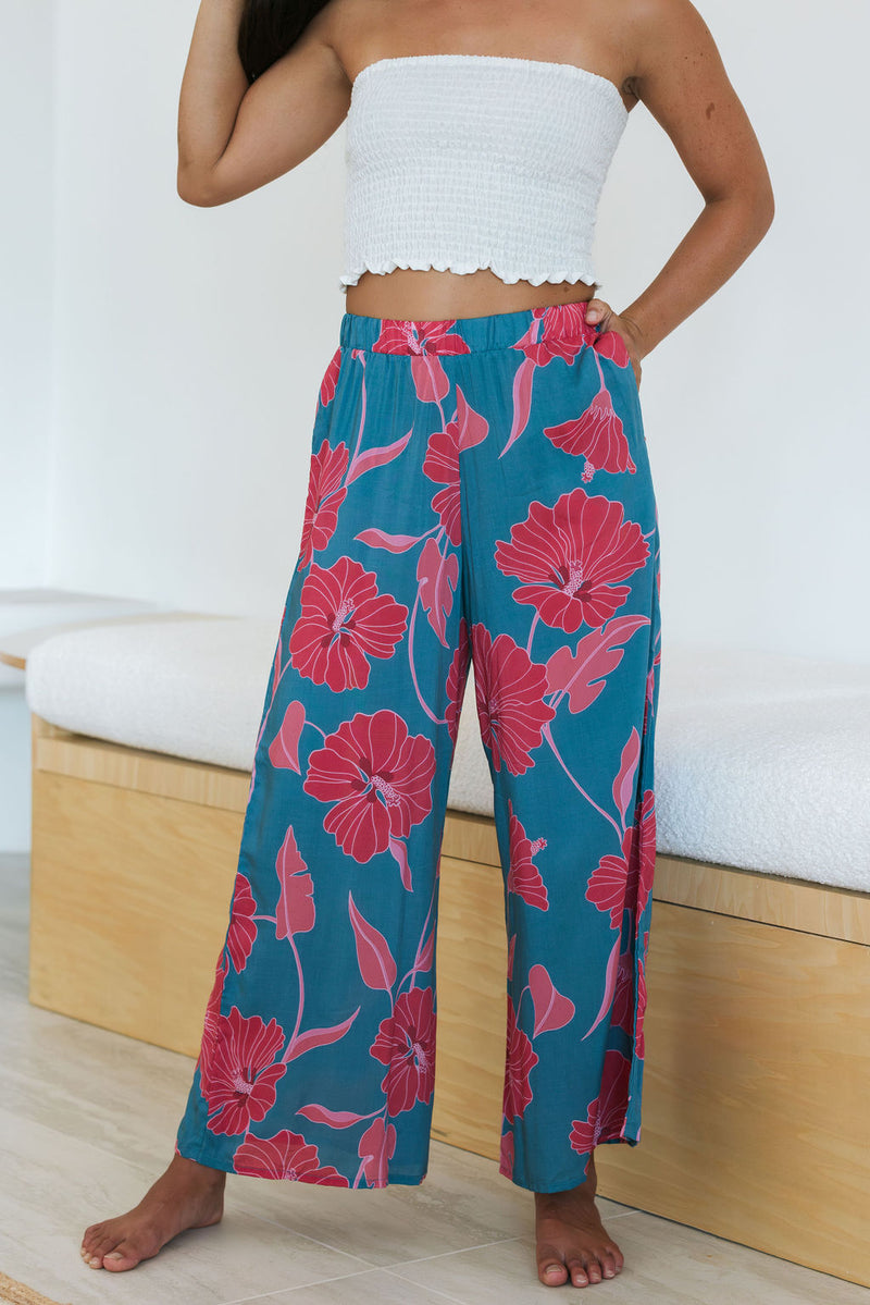 Woman wearing loose blue pants with large pink floral print.