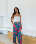 Woman wearing loose blue pants with large pink floral print.