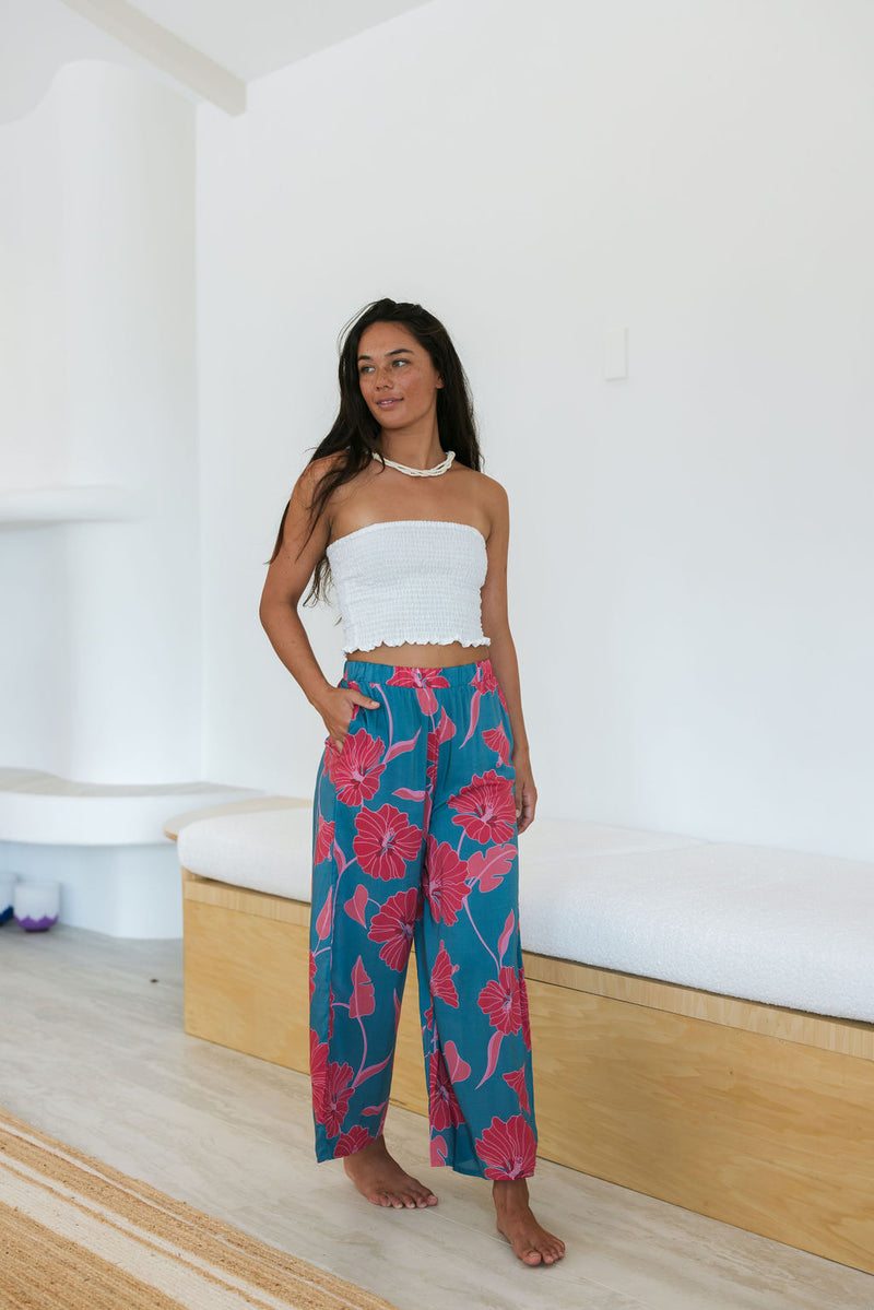 Woman wearing loose blue pants with large pink floral print.