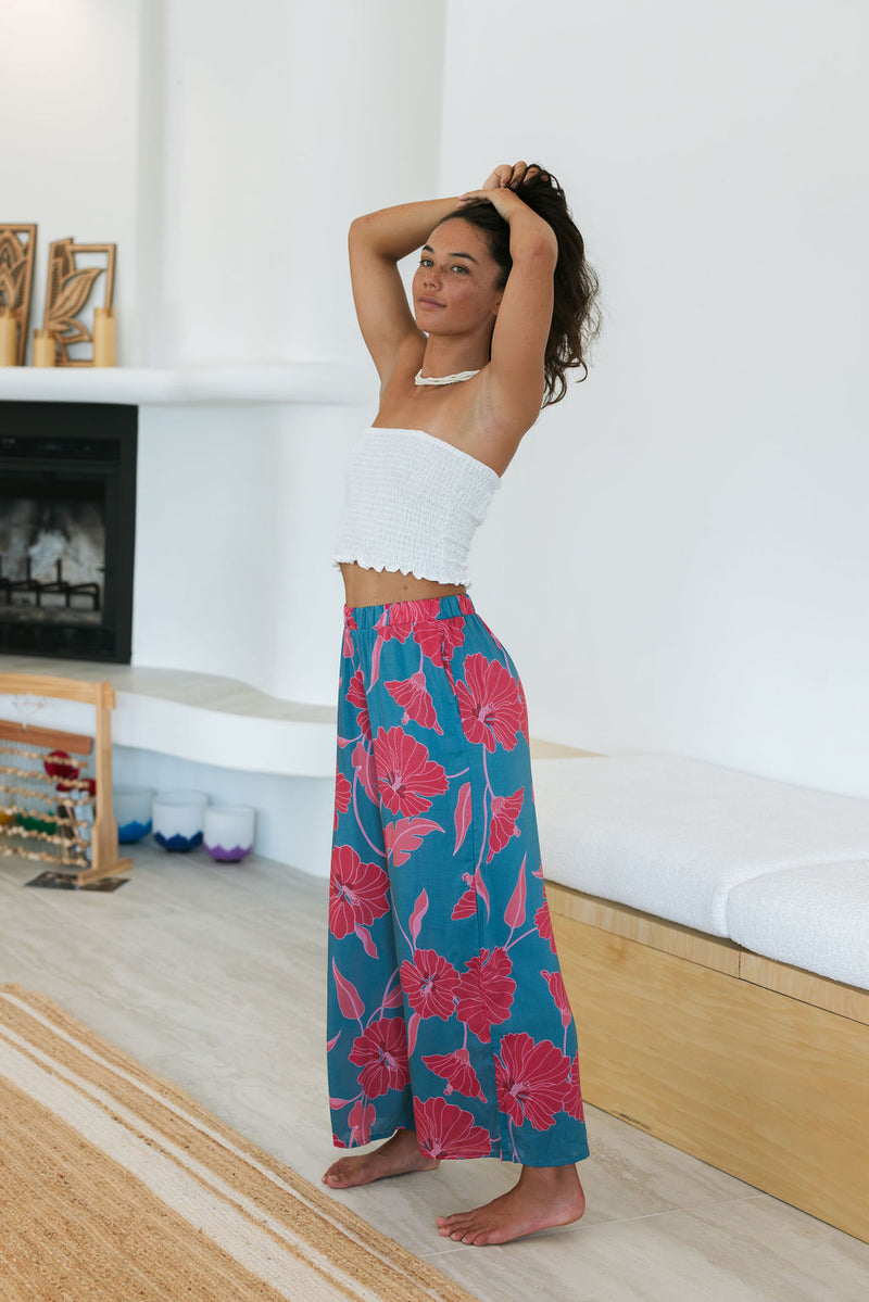 Woman wearing loose blue pants with large pink floral print.