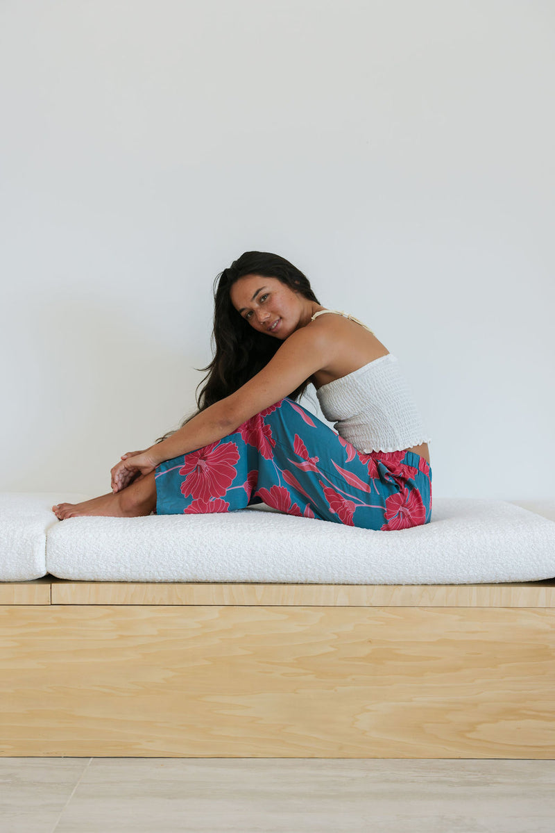 Woman wearing loose blue pants with large pink floral print.