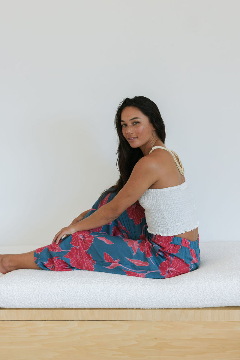 Woman wearing loose blue pants with large pink floral print.