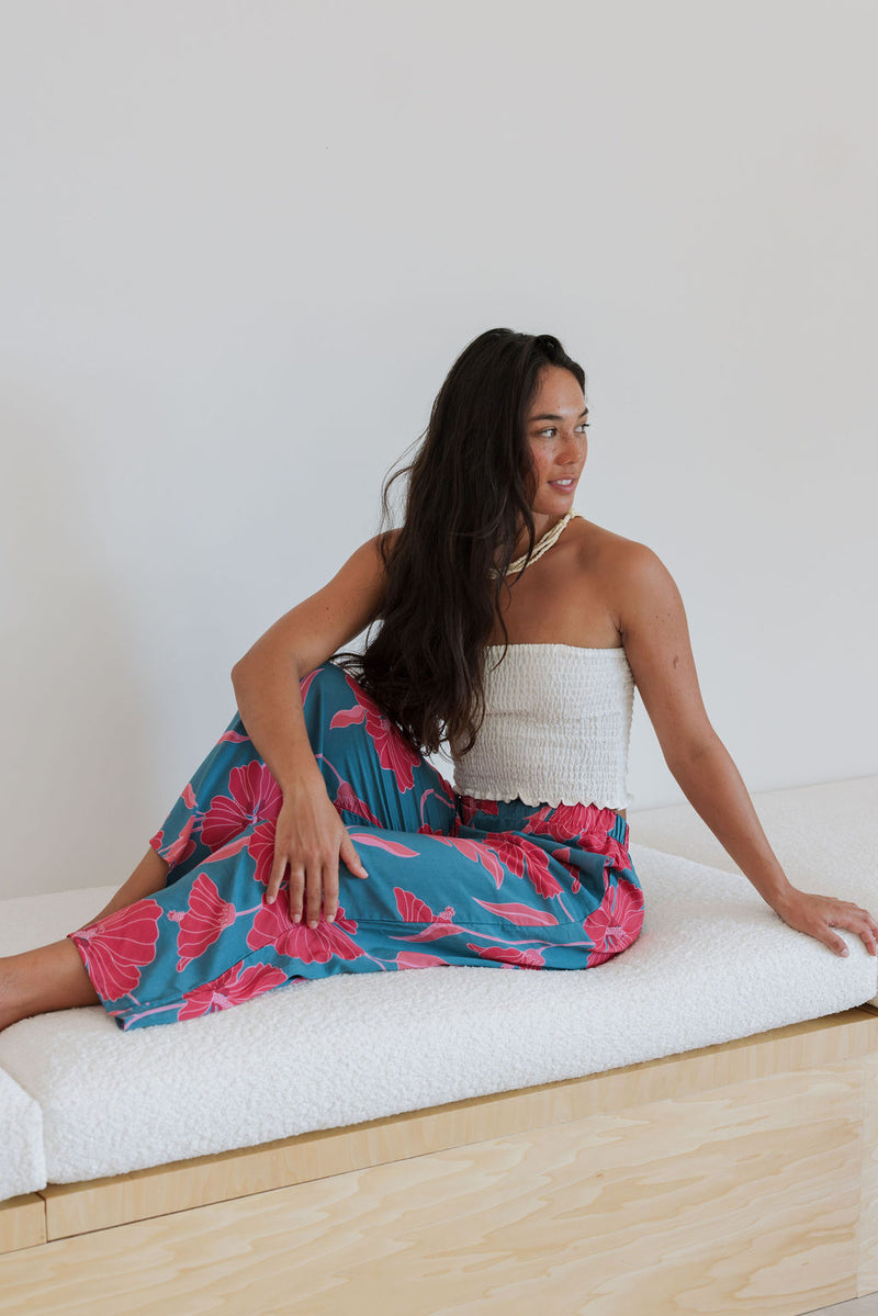 Woman wearing loose blue pants with large pink floral print.