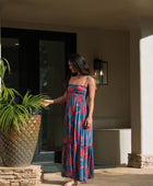 Woman wearing blue sleeveless maxi dress with large pink and red floral print.