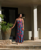 Woman wearing blue sleeveless maxi dress with large pink and red floral print.