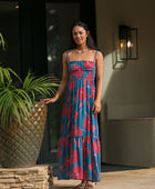 Woman wearing blue sleeveless maxi dress with large pink and red floral print.