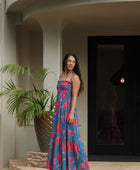 Woman wearing blue sleeveless maxi dress with large pink and red floral print.