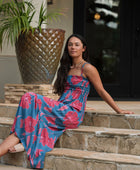 Woman wearing blue sleeveless maxi dress with large pink and red floral print.