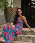 Woman wearing blue sleeveless maxi dress with large pink and red floral print.