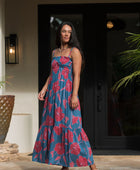 Woman wearing blue sleeveless maxi dress with large pink and red floral print.