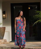 Woman wearing blue sleeveless maxi dress with large pink and red floral print.