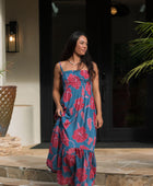 Woman wearing blue sleeveless maxi dress with large pink and red floral print.