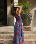 Woman wearing blue sleeveless maxi dress with large pink and red floral print.