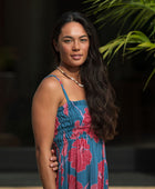 Woman wearing blue sleeveless maxi dress with large pink and red floral print.