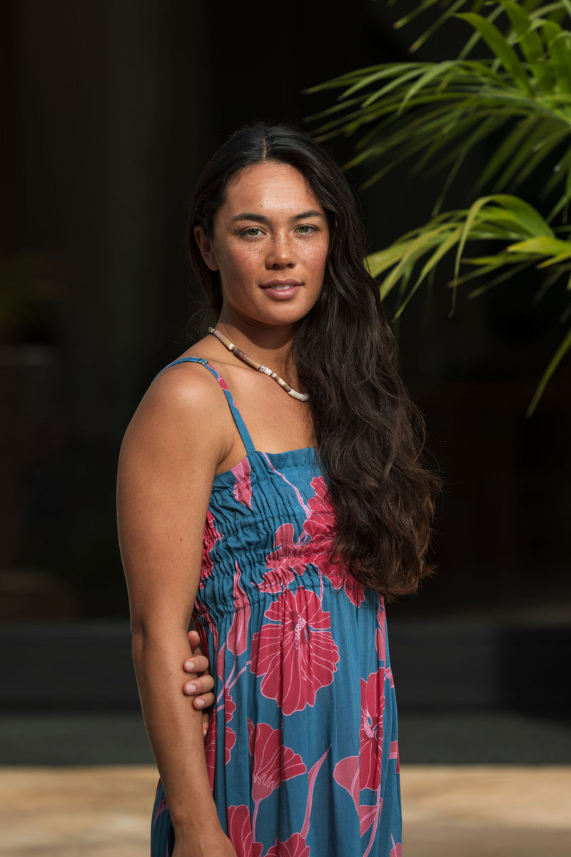 Woman wearing blue sleeveless maxi dress with large pink and red floral print.