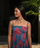 Woman wearing blue sleeveless maxi dress with large pink and red floral print.