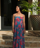 Woman wearing blue sleeveless maxi dress with large pink and red floral print.