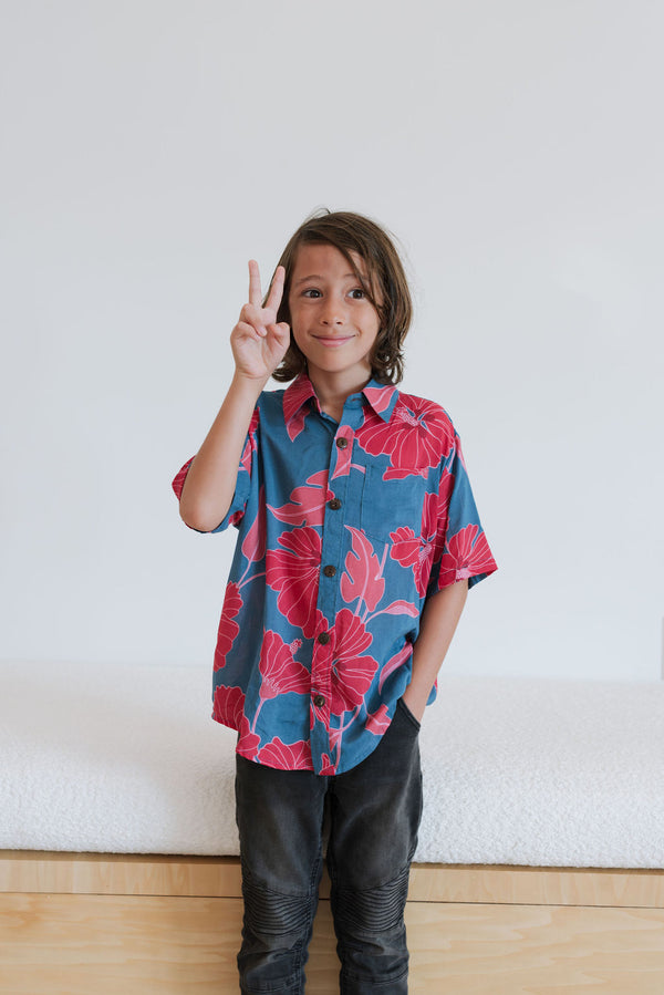 Boy in blue button up shirt with large pink and red floral print.