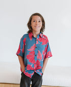 Boy in blue button up shirt with large pink and red floral print.