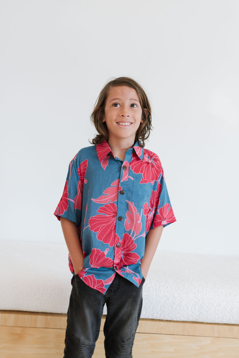 Boy in blue button up shirt with large pink and red floral print.