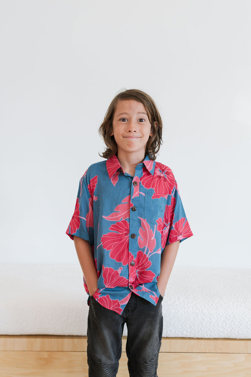 Boy in blue button up shirt with large pink and red floral print.