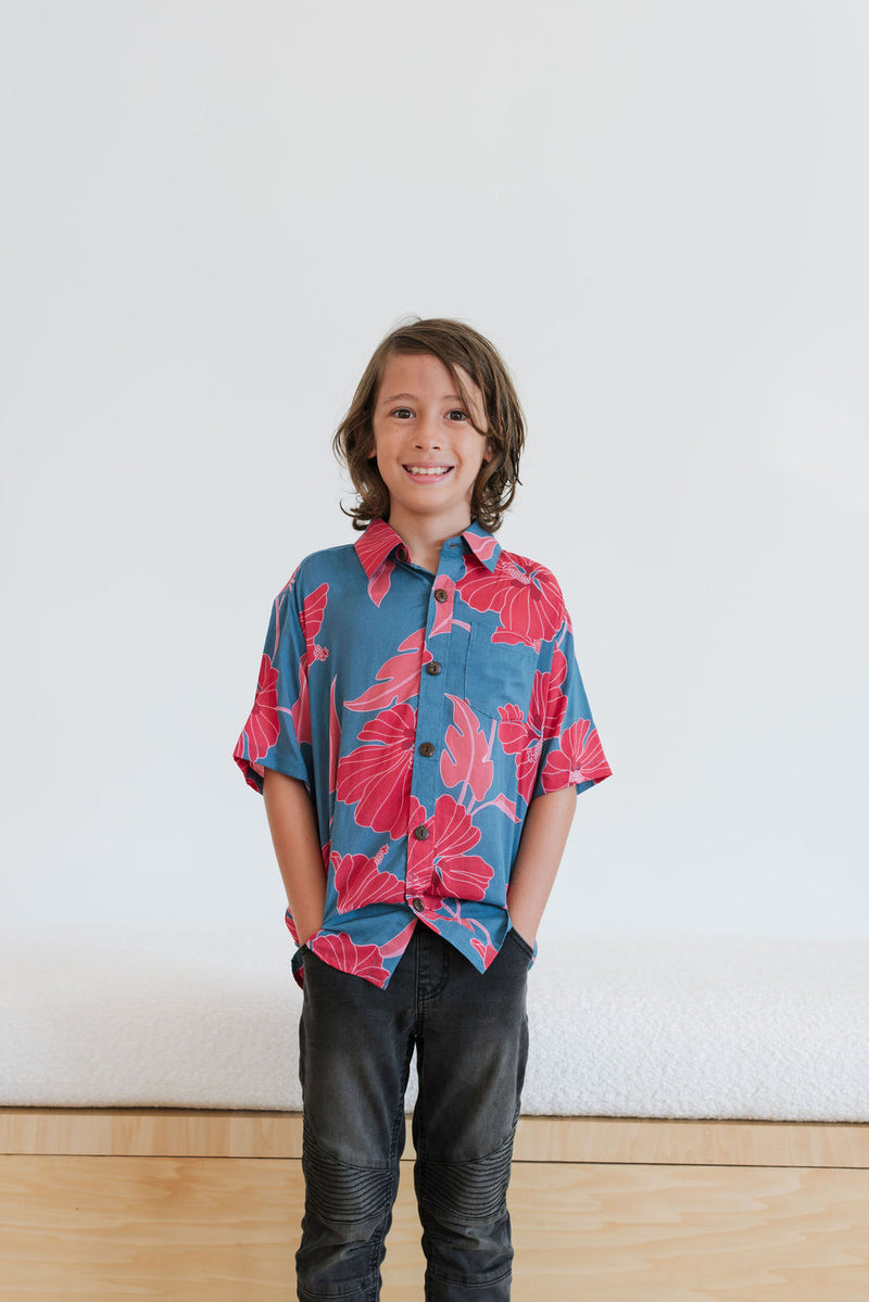 Boy in blue button up shirt with large pink and red floral print.