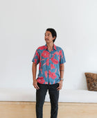 Man in blue button up shirt with large pink and red floral print.