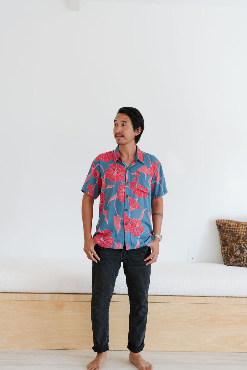 Man in blue button up shirt with large pink and red floral print.