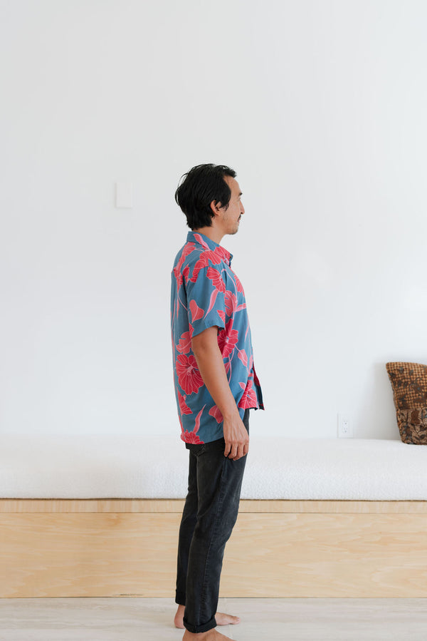 Man in blue button up shirt with large pink and red floral print.