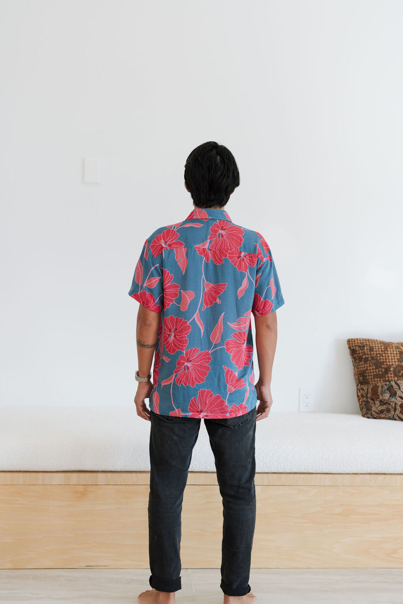 Man in blue button up shirt with large pink and red floral print.